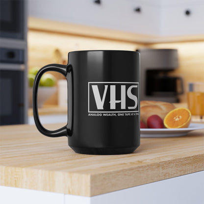 black coffee mug featuring VHS analog wealth design in white displayed on kitchen counter
